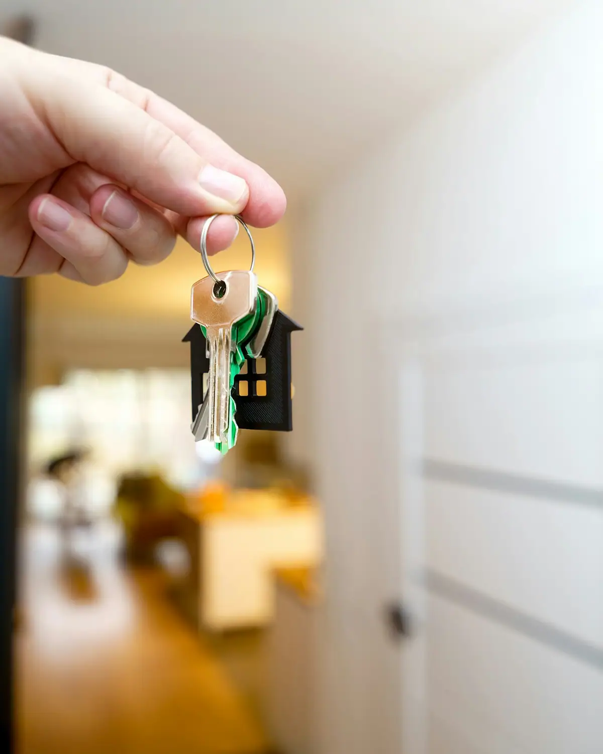 A house key handed over on a house-shaped keychain